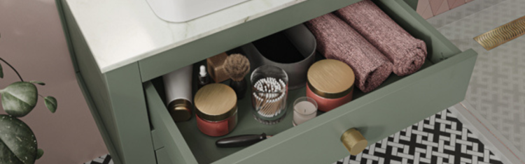 Close up image of a green cabinet drawer filled with cotton buds and scented candles