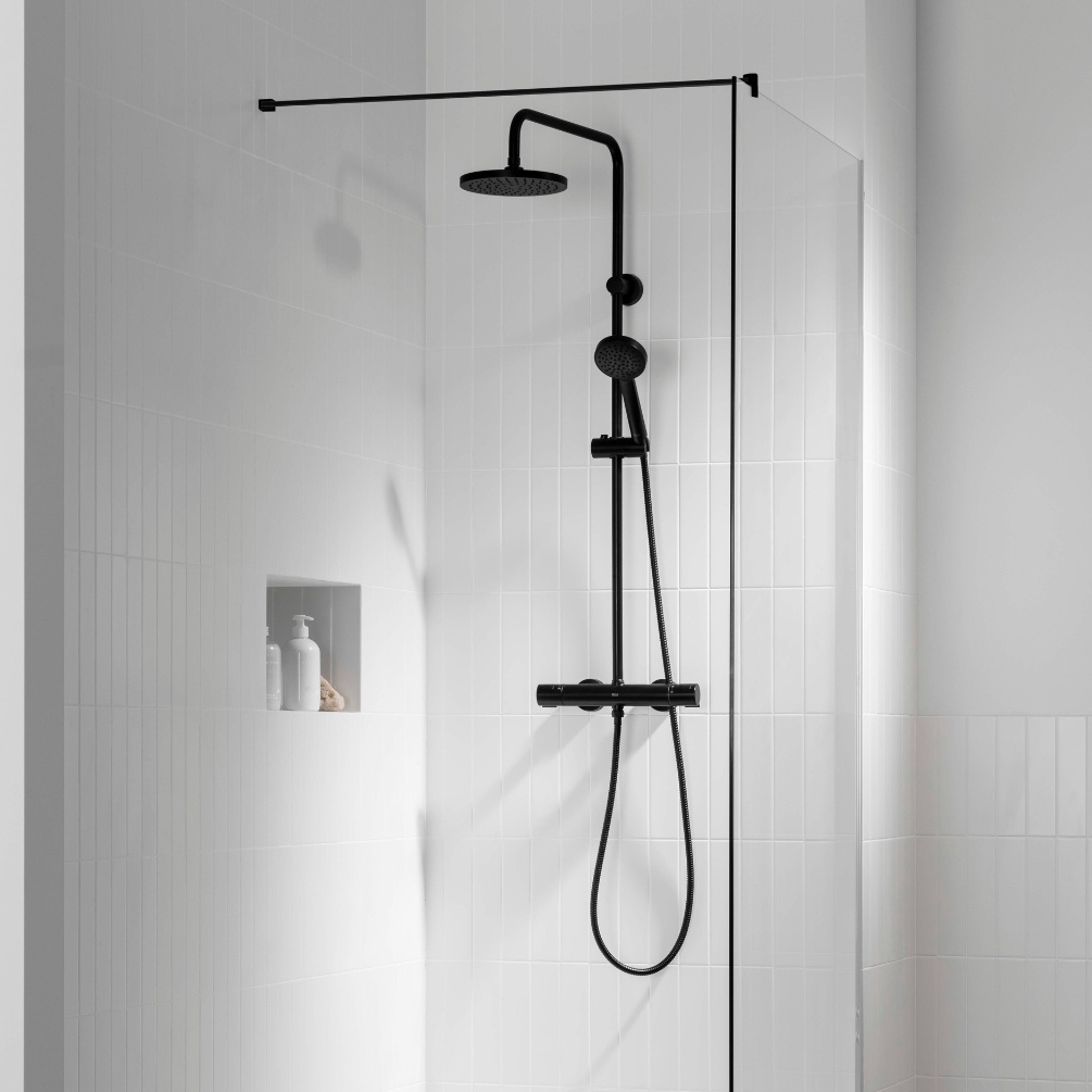 Lifestyle image of the Roca Victoria-T Matt Black Thermostatic Shower Column mounted in a shower enclosure with niche