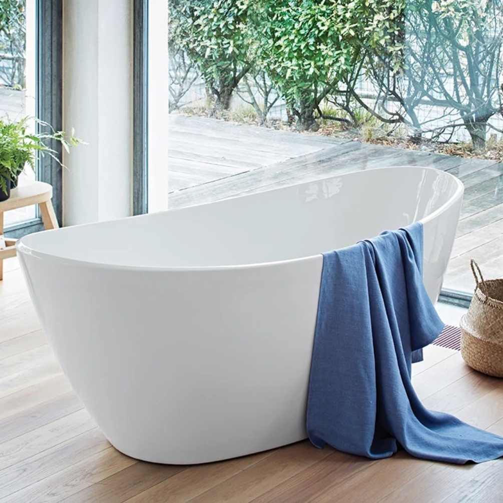 product lifestyle image of waters infinity spa 1670mm freestanding bath with blue towel hanging over edge in front of window
