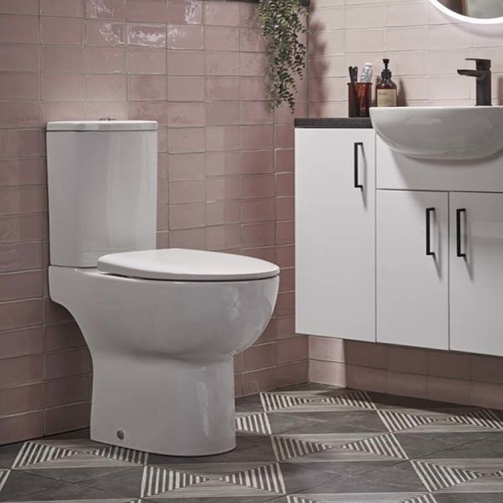 Lifestyle image of the Tavistock Loft Close Coupled Open Back Toilet installed against a pink tiled bathroom wall