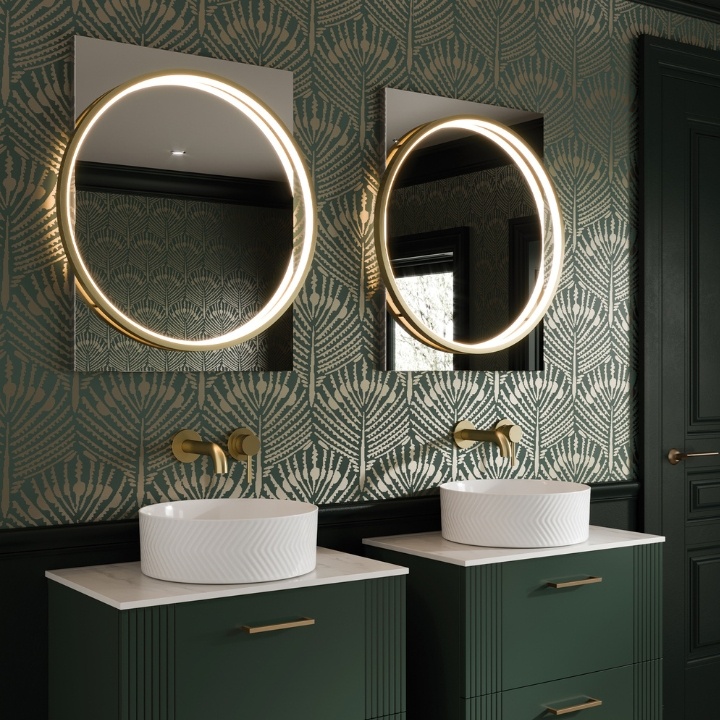 An Art Deco inspired set of vanity units and round mirrors in a green bathroom with floral motif wallpaper