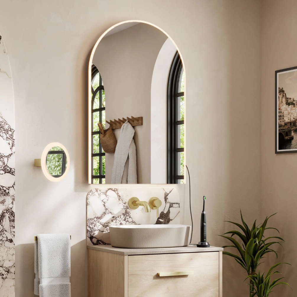 Lifestyle image of the hib. Alba Arch 600mm x 900mm LED Mirror mounted on a white wall and above a freestanding basin & furniture
