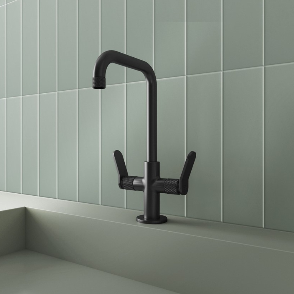 Lifestyle image of the Crosswater Calix Matt Black Tall Basin Mixer installed on the deck of a green basin