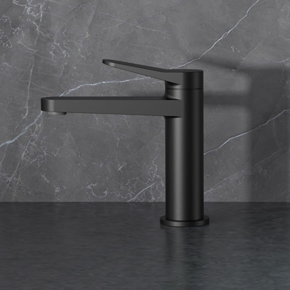 Lifestyle image of RAK Petit Round Standard Basin Mixer black mounted on black surface against grey marble wall.
