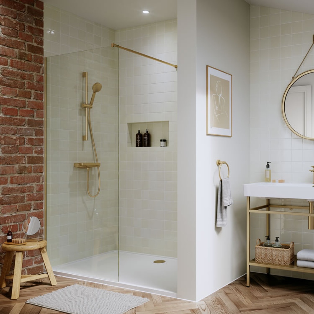 Photo of the Hoxton Shower Set with Outlet Elbow in Brushed Brass with other brushed brass accessories, white tiled wall, and parquet flooring
