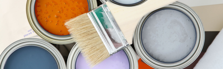 Close up image of a paintbrush placed on top of paint cans