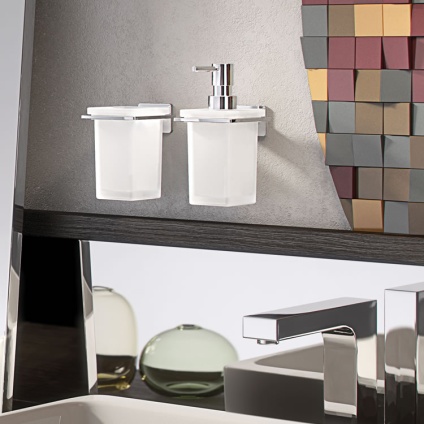 Lifestyle image of Origins Living Gedy Atena Soap Dispenser mounted on a grey wall above a white sink and chrome tap.