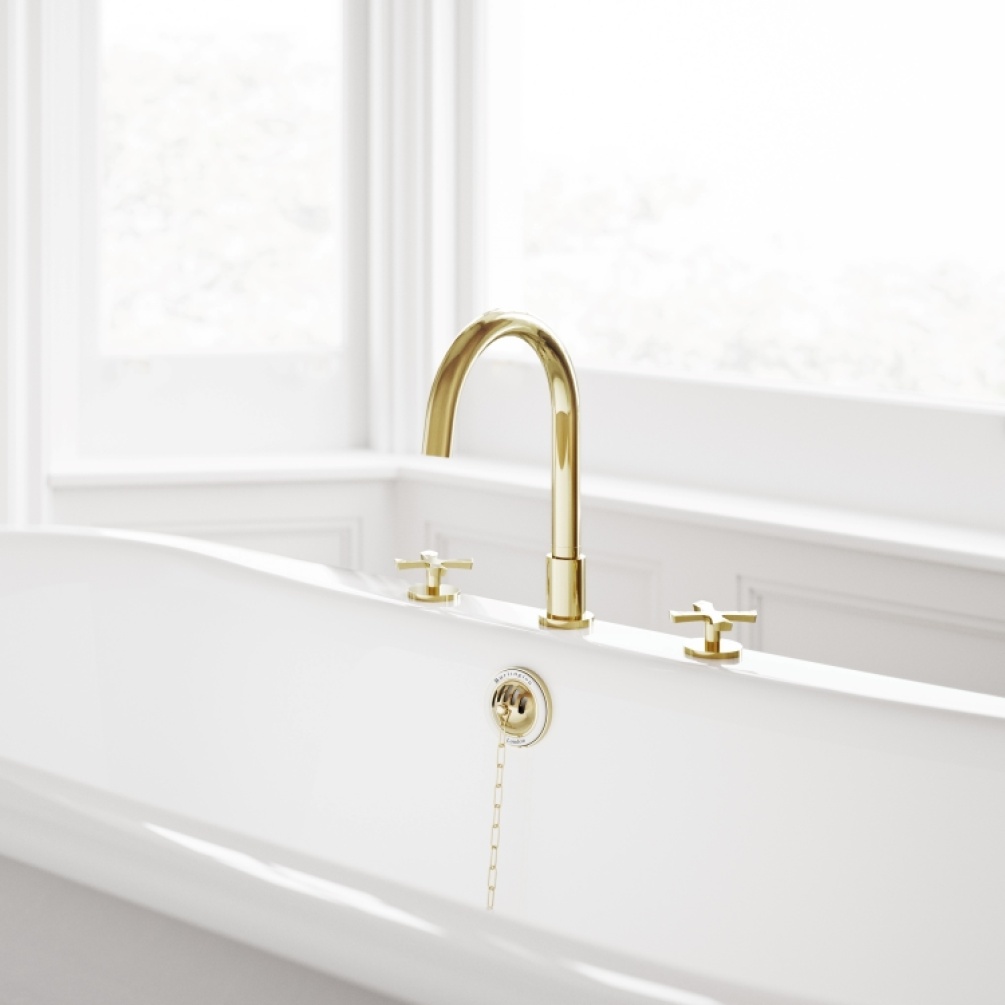 Product Lifestyle image of the Burlington Riviera Gold 3 Tap Hole Bath Mixer mounted on bath in white bathroom with windows behind