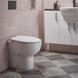 Lifestyle image of the Tavistock Loft Back To Wall Rimless Toilet installed against a pink tiled bathroom wall