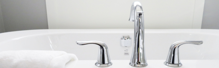 Close up image of deck mounted bath tap with separate spout and handles
