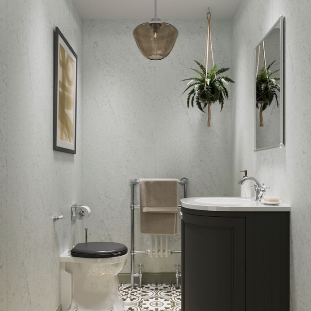 Lifestyle image of the Showerwall Laminate Pebble 2440mm x 1200mm Square Cut Hydrocore Wall Panel - SW101 in a small bathroom with back to wall toilet, basin & vanity unit, and radiator