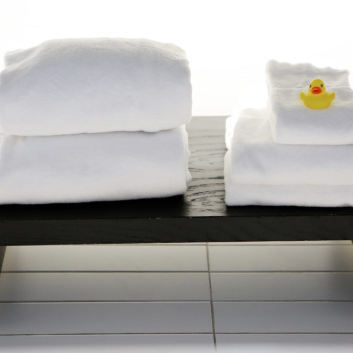 Close up image of two piles of towels on a dark wood bench