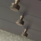 Close up product lifestyle image of three Roper Rhodes Brushed Bronze Fresno Knobs